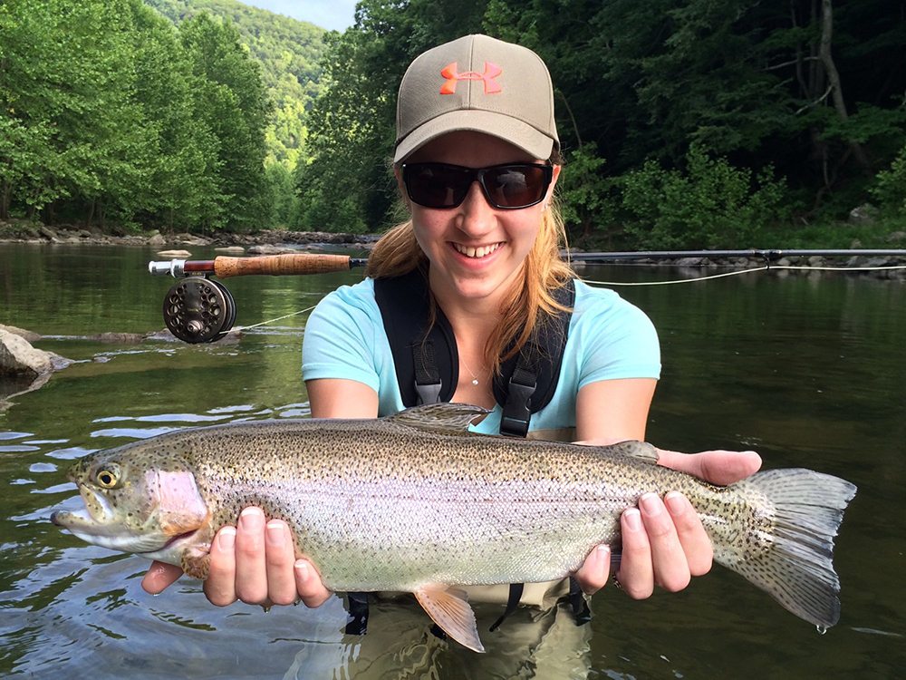 Woman holding a trout fish at Harman's Luxury Log Cabins in West Virginia.