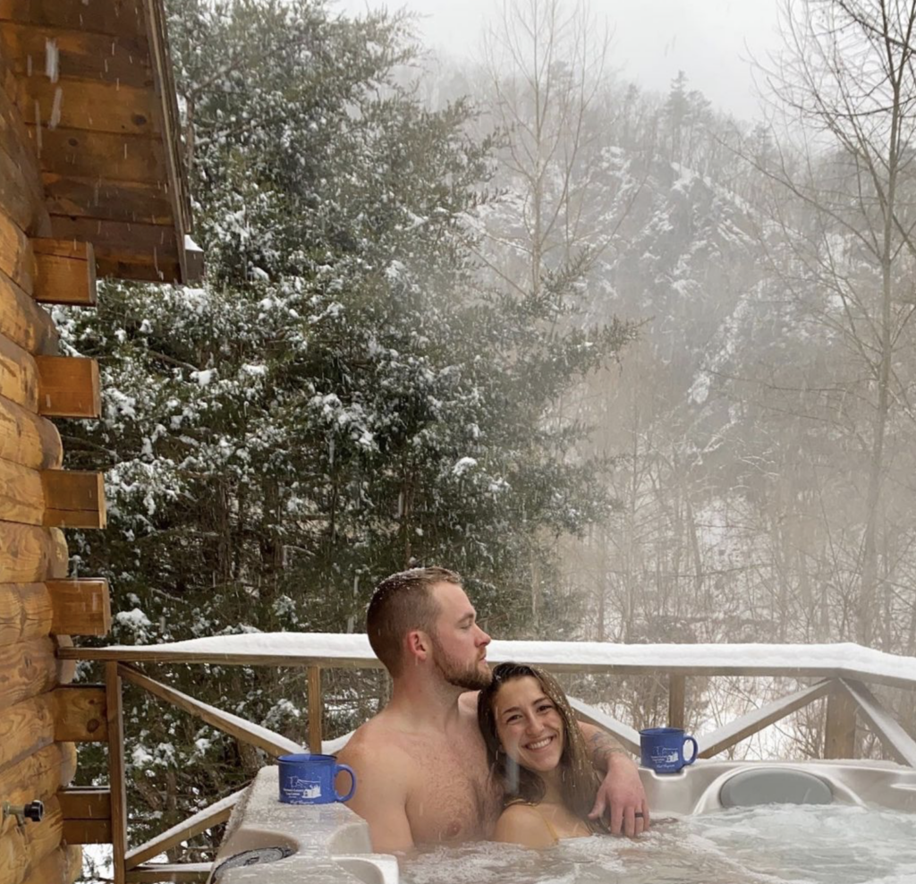 Young couple enjoying the outdoor hot tub at Harman's Log Cabins in West Virignia.